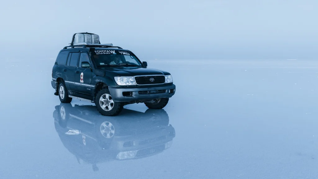 Black SUV parked on a reflective surface with a clear sky background.