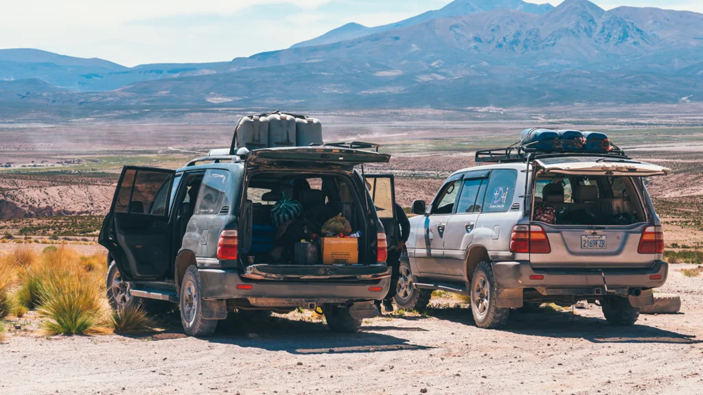Two off-road SUVs parked in a desert landscape with mountains in the background.